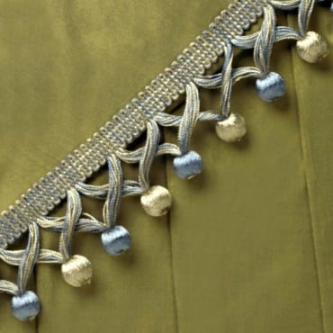 Add a unique touch to your home furnishings with our Covered Beaded Fringe. The fringe is made with an overlapping criss-cross design that features covered round beads at the bottom of the trim. The braided guimp attached to the fringe can easily be sewn 